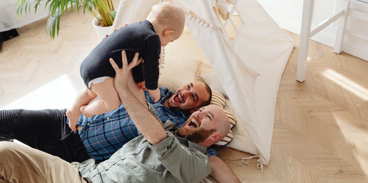 two fathers playing with infant