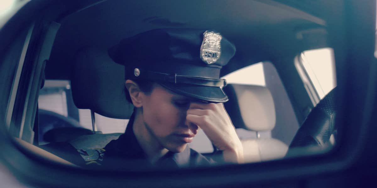 cop in the front seat of her car, looking stressed