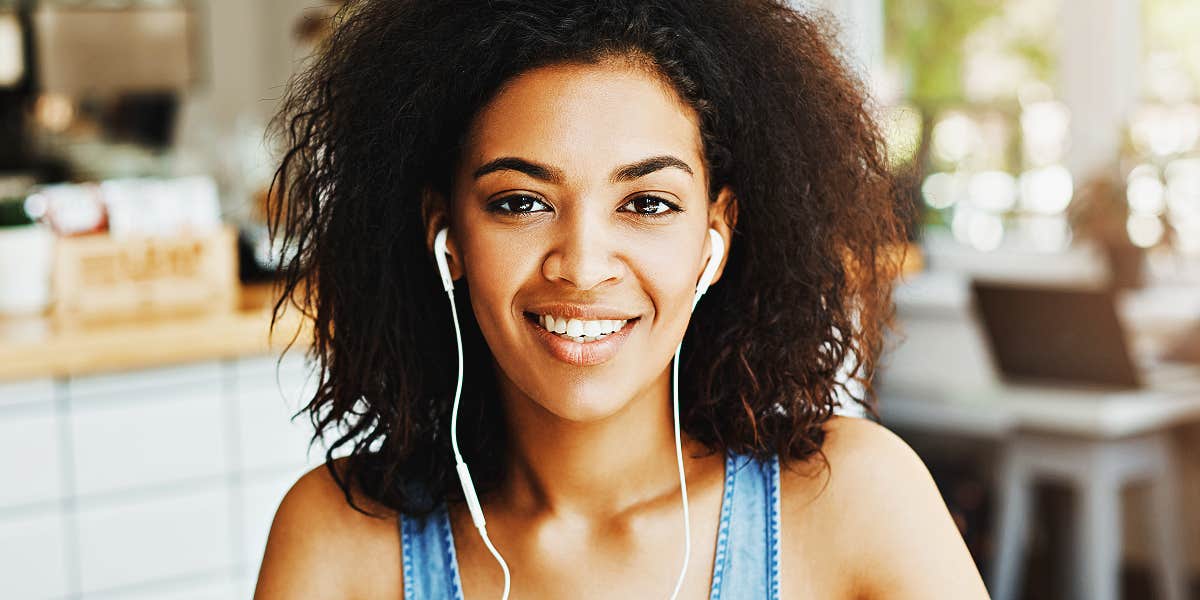 Black woman in headphones, smiling at camera