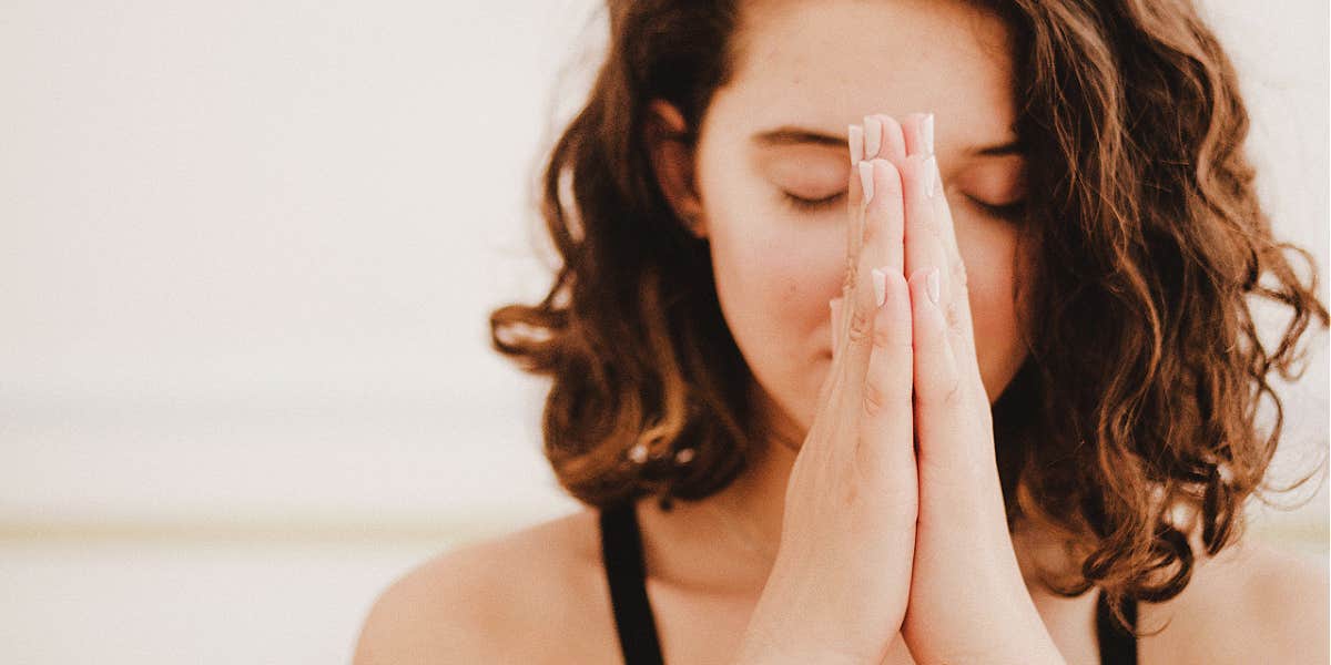 Harness the power of gratitude woman, eyes closed, hands to head in prayer pose