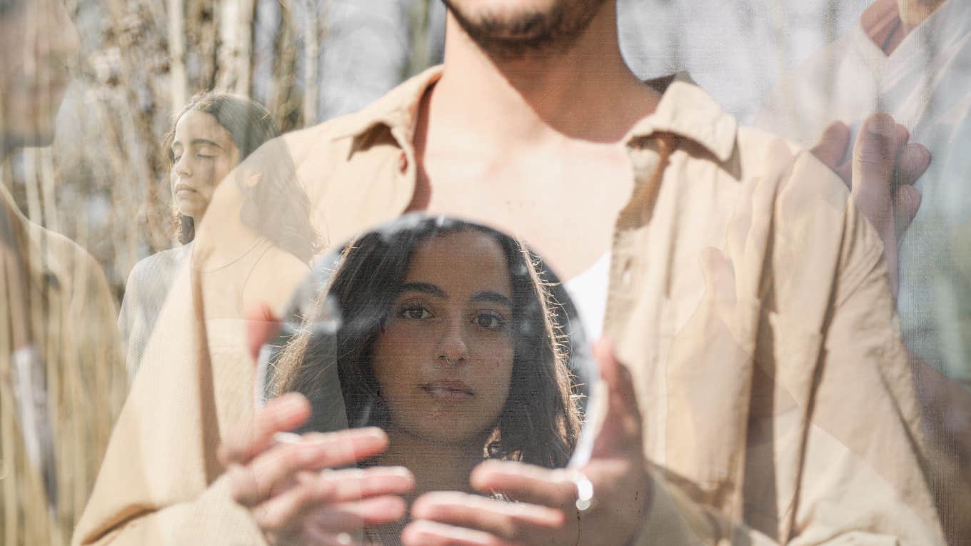 man holding a mirror with a reflection of his partner in it