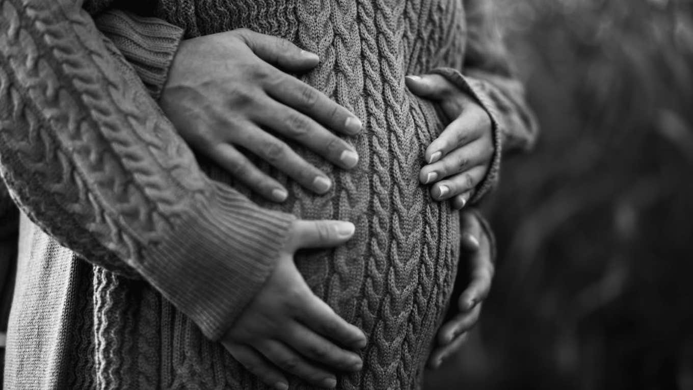 pregnant couple in black and white photo cradling pregnant belly