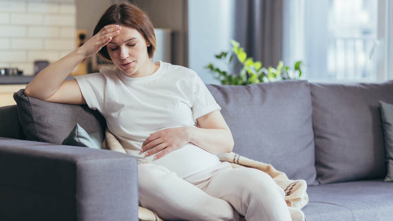 upset pregnant woman sitting on the couch