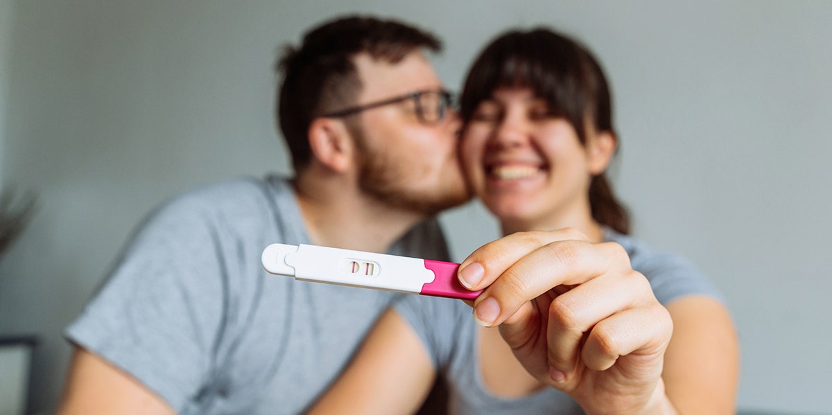 woman holding pregnancy test with husband
