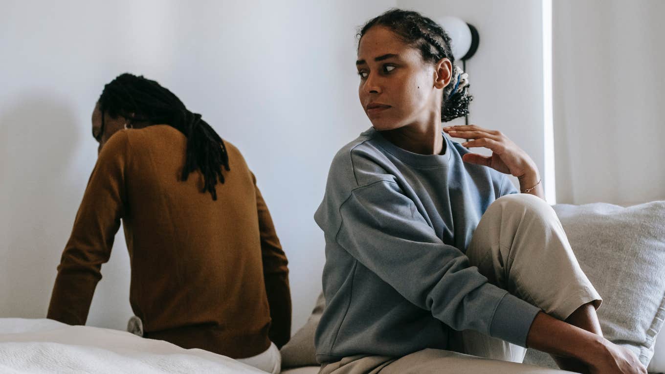 man and woman facing away from each other on a bed