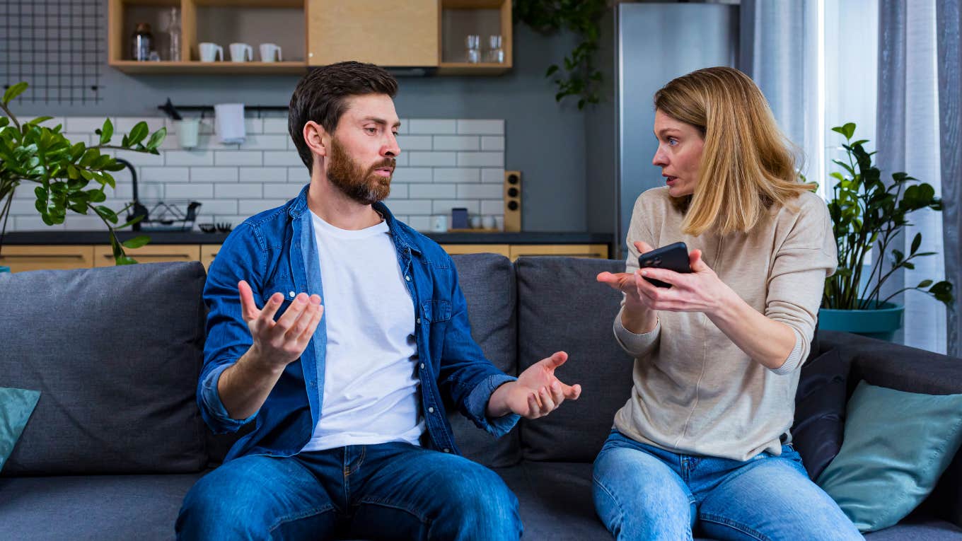 woman holding man's phone accusing him of cheating