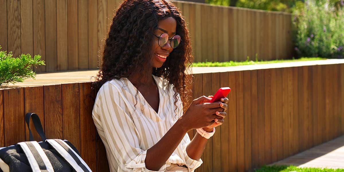 woman sitting outside texting on her phone