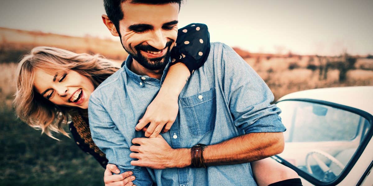 smiling couple with woman hugging man from behind