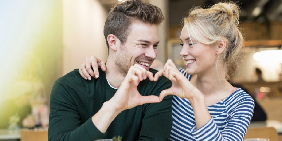 man and woman making heart with their hands
