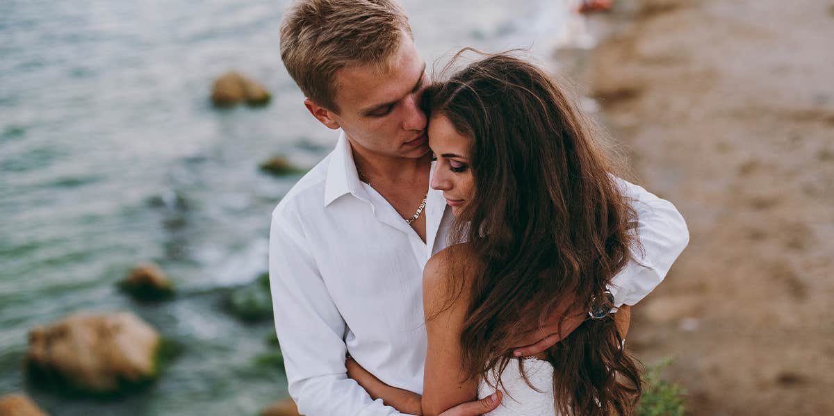 man hugging woman overlooking ocean cliff