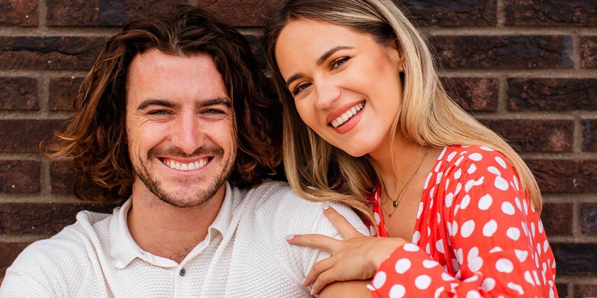 smiling couple against brick wall