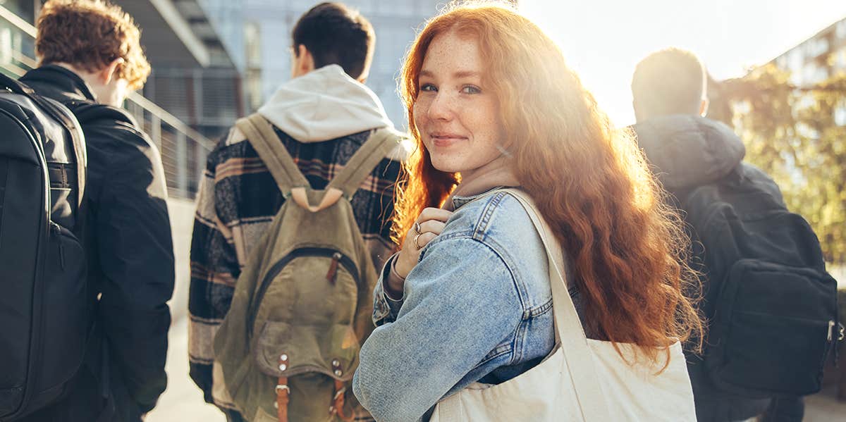 teenager with backpack looking over shoulder 