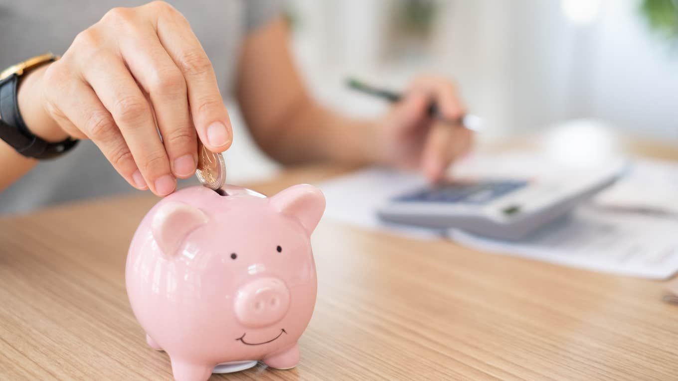 man putting money in a piggy bank