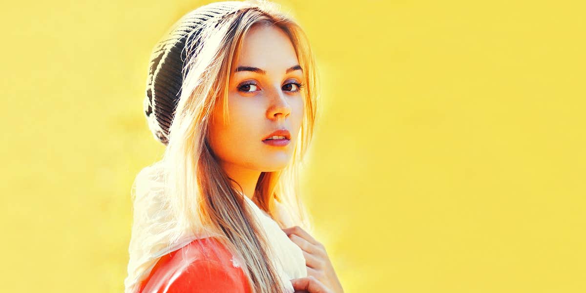 Young blonde woman against yellow wall