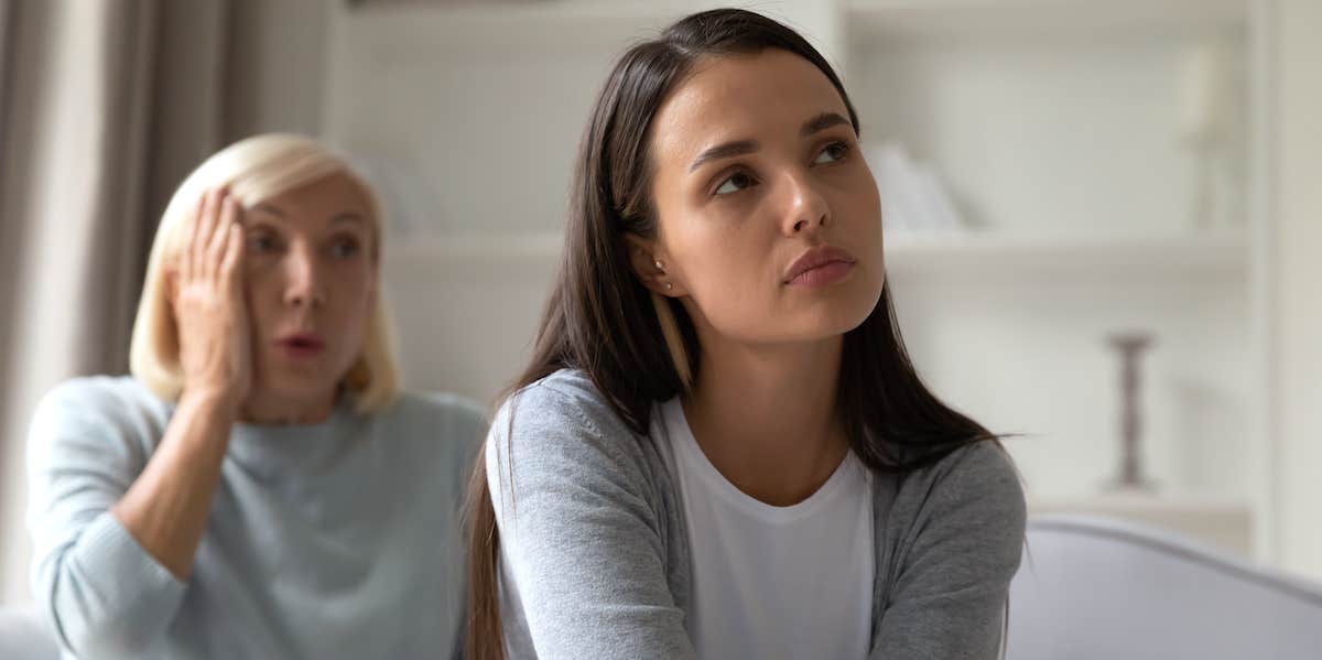 disbelieving older woman sits behind frustrated younger woman who has turned her back on the older woman