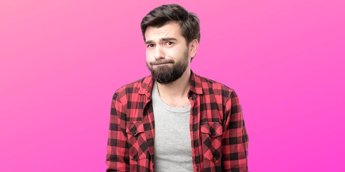 A regretful looking man stand in front of a hot pink background