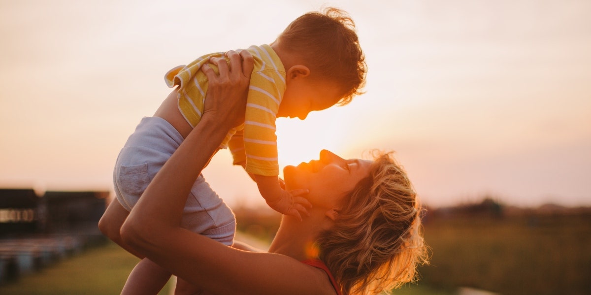 mother playing with son outside during sunset