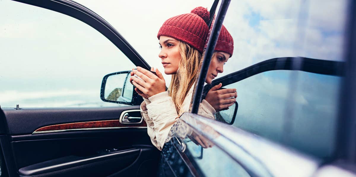 Pensive woman sips coffee in a car