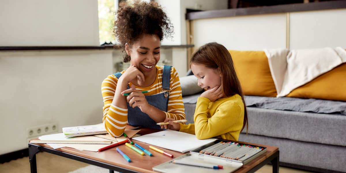 Babysitter drawing with little girl at table