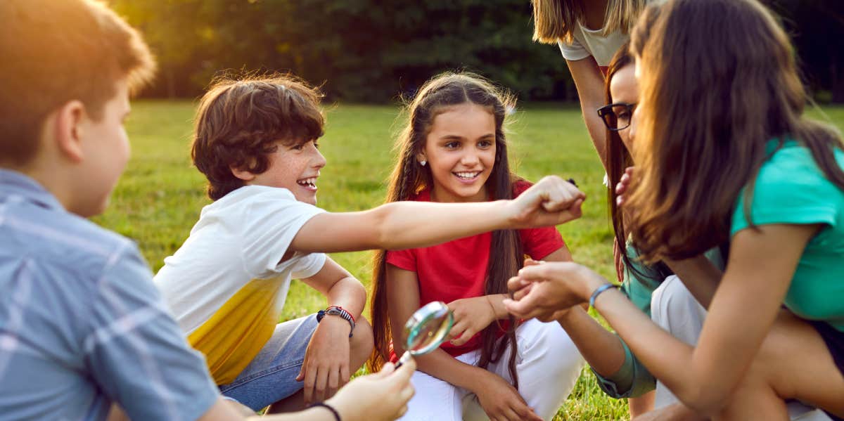 School kids on field trip sitting on grass with each other