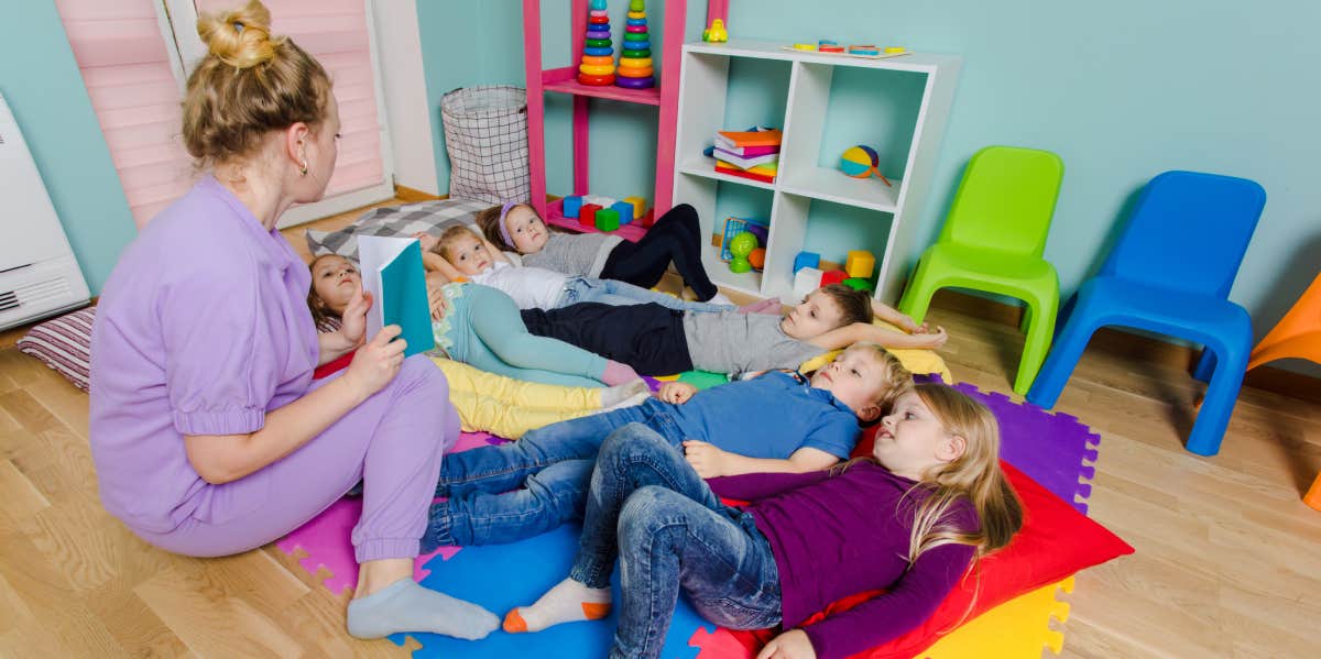 Mom Gets Into 'Dispute' With Daughter's Daycare After Noticing Her Naptime Is Off Schedule teacher reading stories to children at daycare
