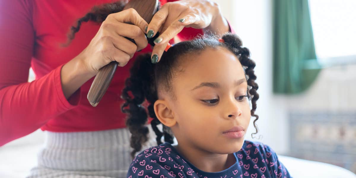 woman fixing little girl's hair