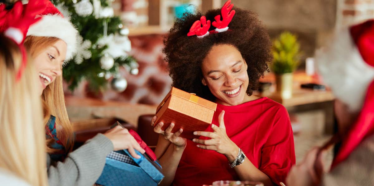 friends giving christmas gifts to each other while sitting at a table