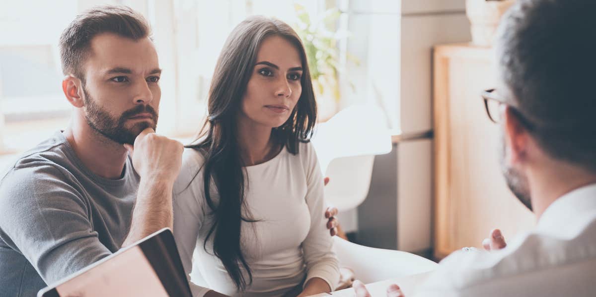 Couple sitting in office and listening to doctor at his desk