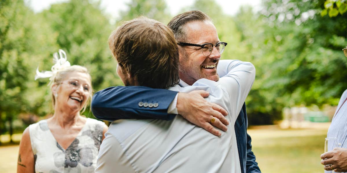 Man Sparks Debate After Asking His Wife Not To Go To His Son's Wedding father embracing the groom at wedding