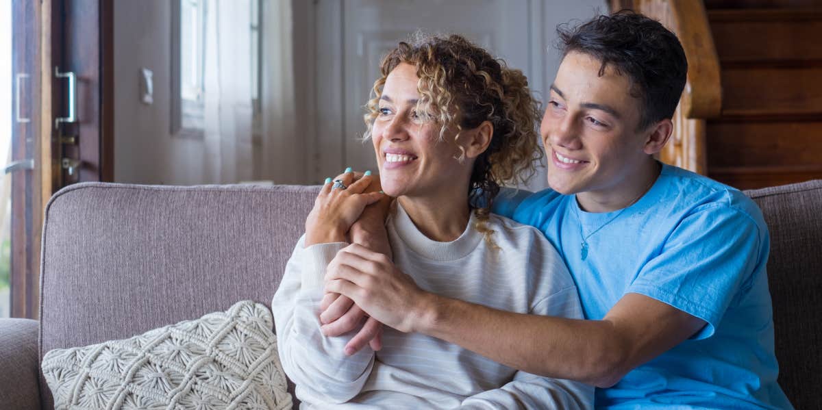 mom and teenage son embracing while sitting on a couch