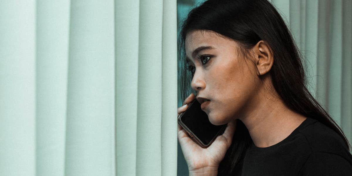 woman on phone looking out window