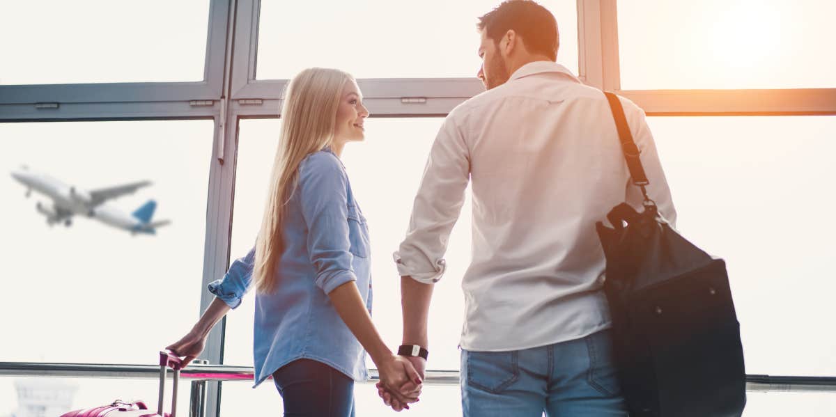 couple holding hands with suitcases to travel