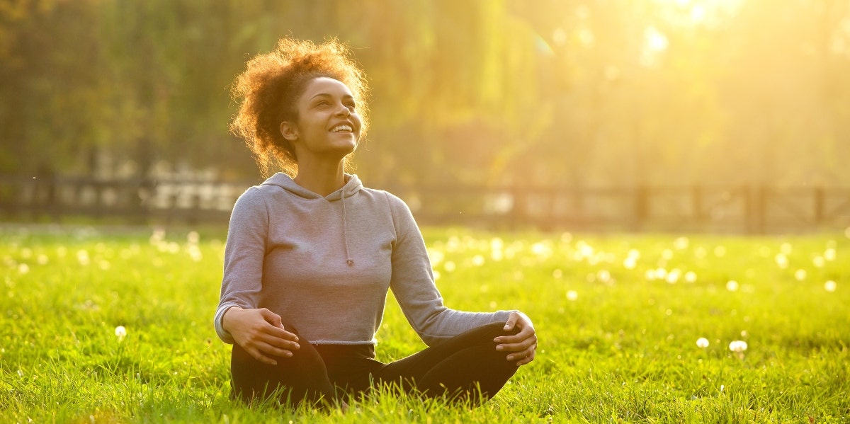 reiki tummo woman sitting cross-legged on the grass under the sun