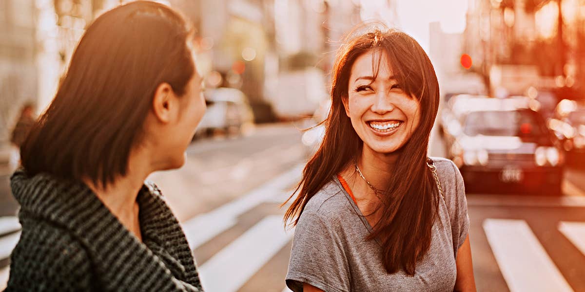 two women walking across a street, relating and talking