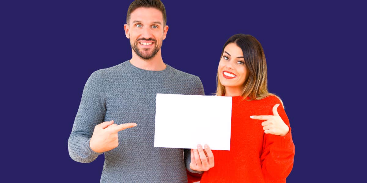 man and woman smiling and pointing at paper they're both holding onto