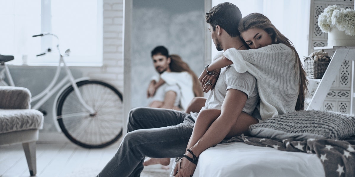 relationship expectations woman hugging man from the back while sitting in bed