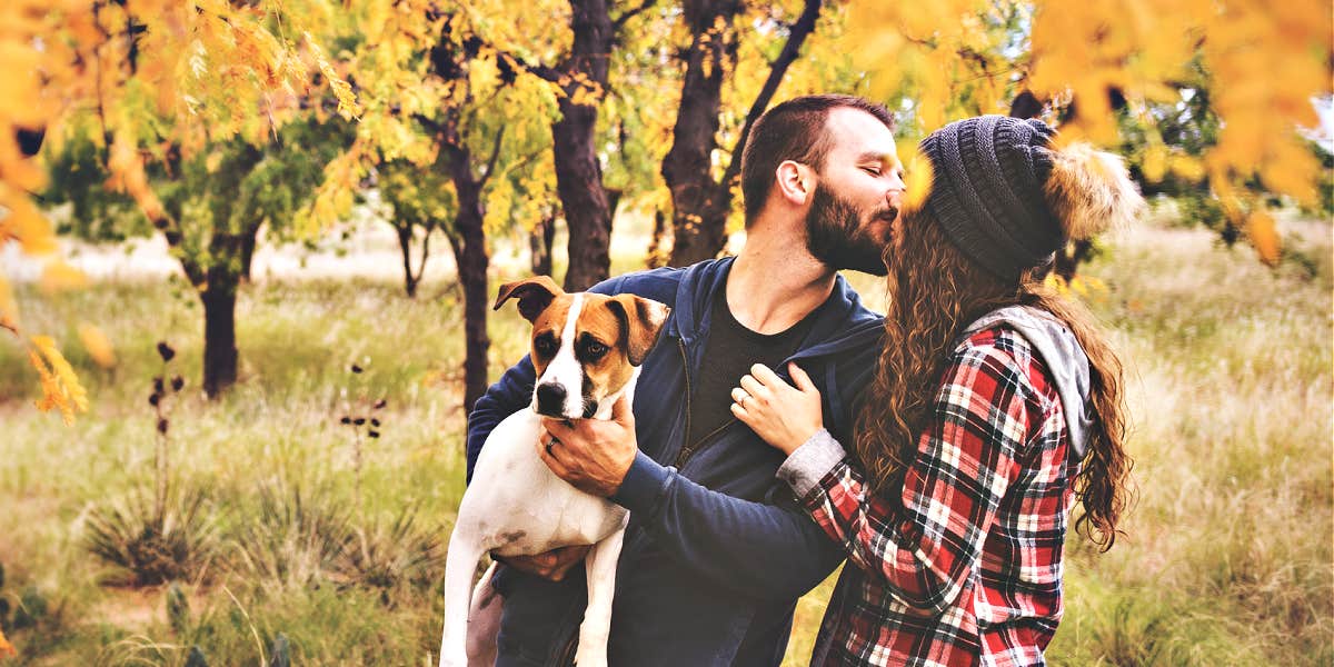 couple kissing in the trees with their dog