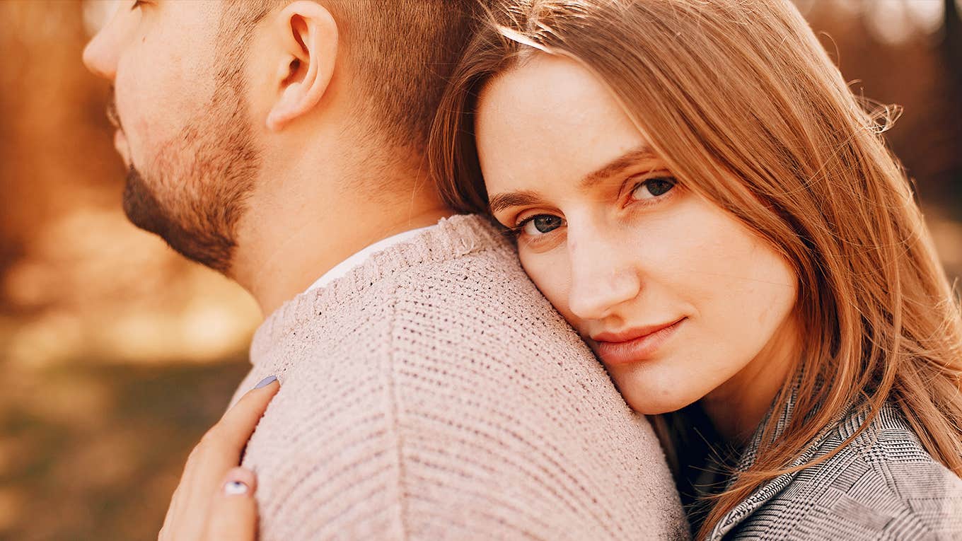 woman looking into the camera while hugging her male partner
