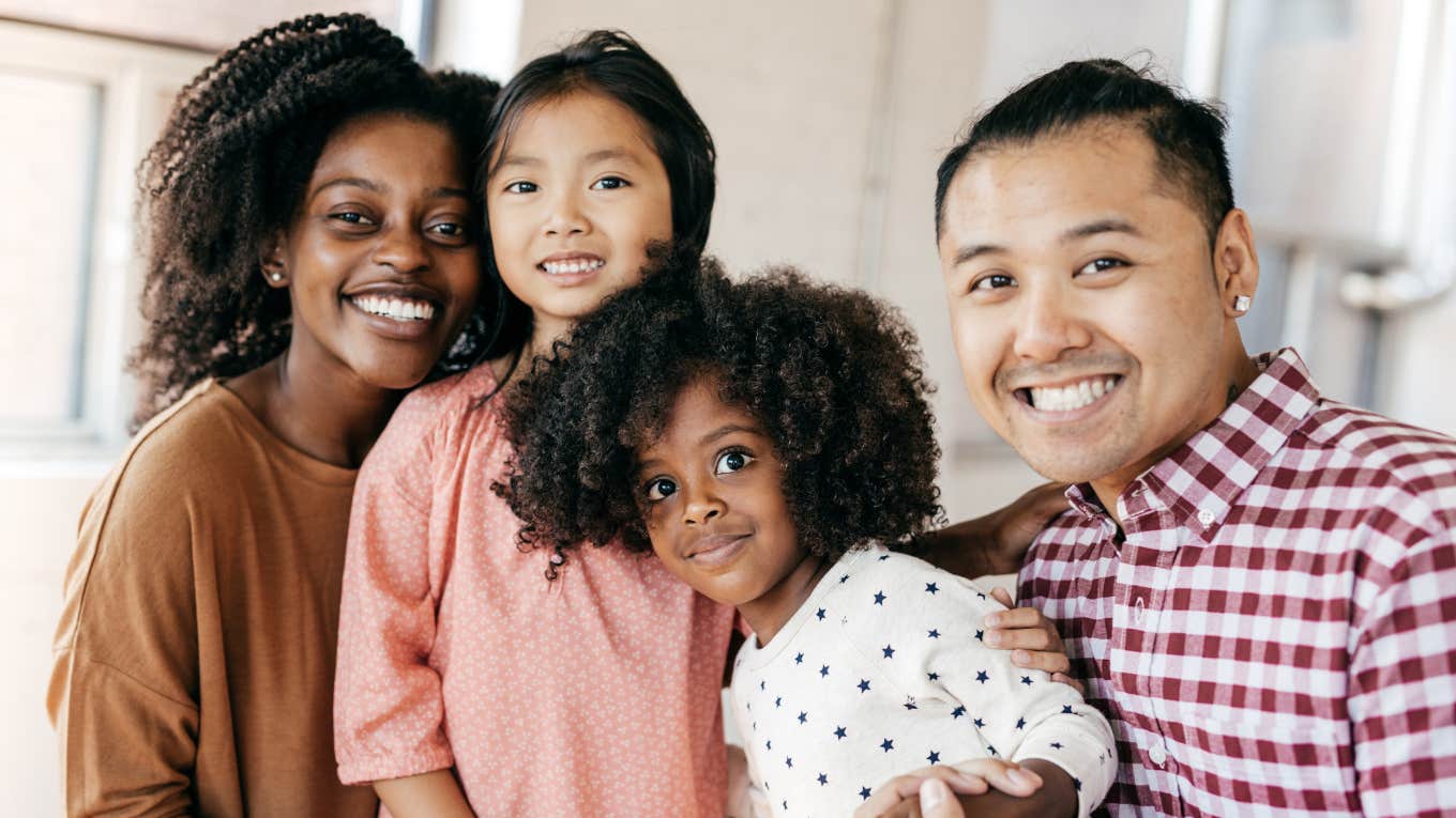 Two parents smiling with their young children. 