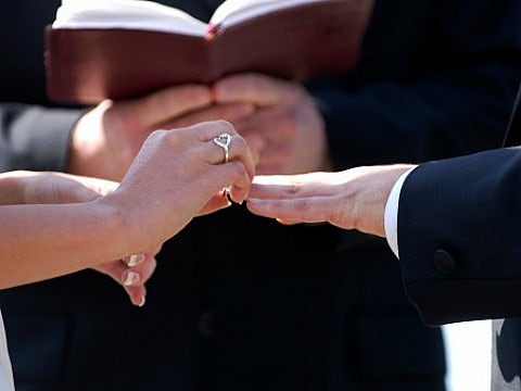 couple putting ring on finger in marriage ceremony