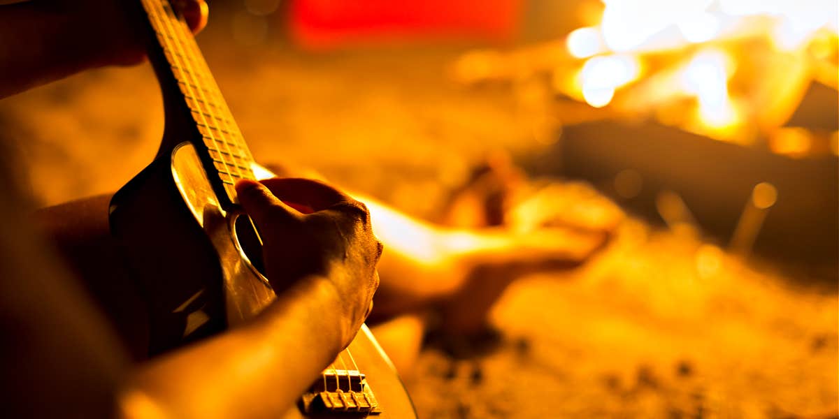 Ritual of burning fallen wood person relaxing with a guitar, sitting near a peaceful fire