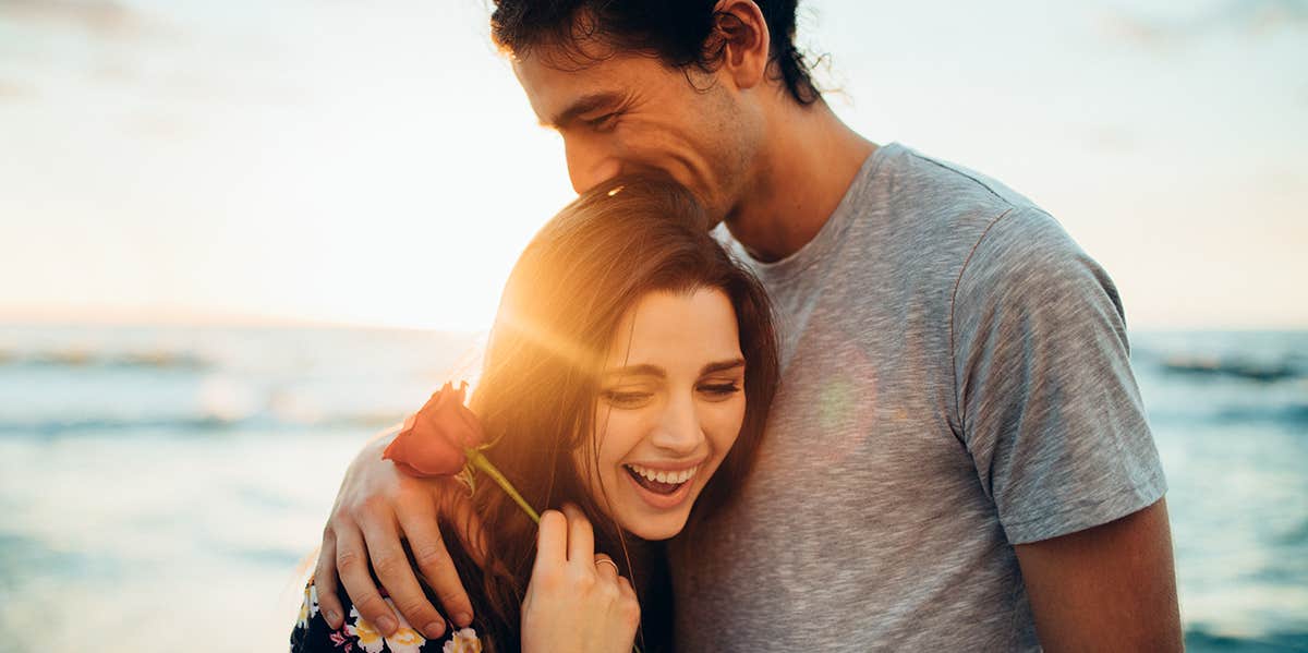 man embracing woman at sunset