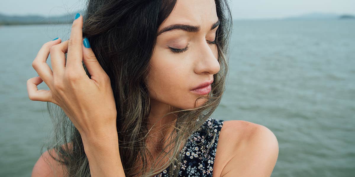 6 Ways You Sabotage Relationships Because You're Afraid Of A Broken Heart woman tucking hair behind face