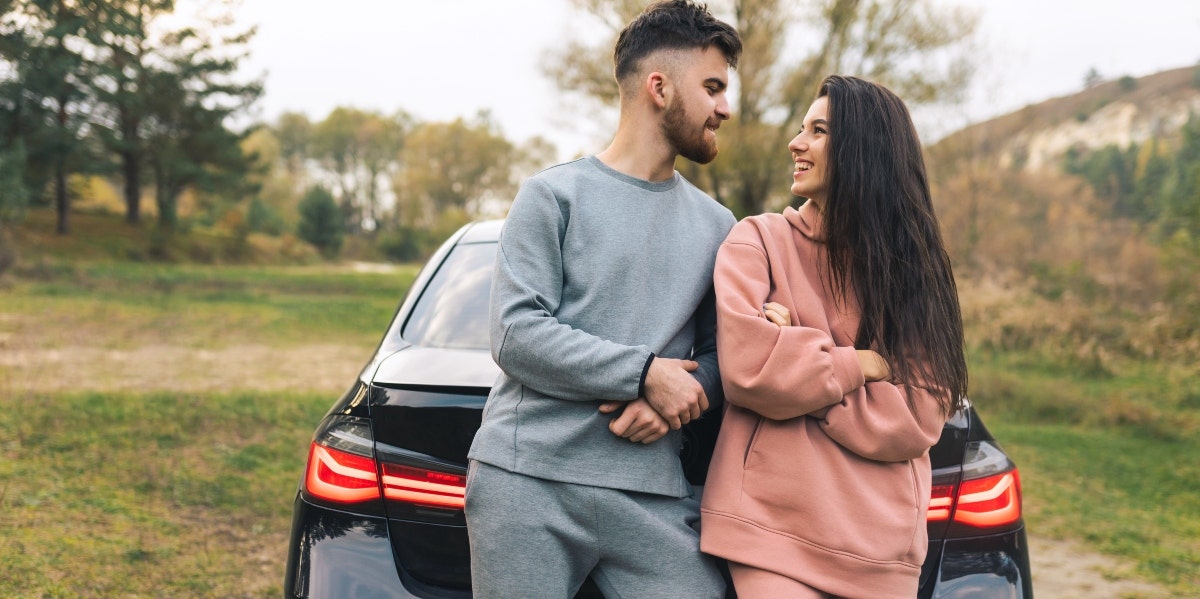 couple in sweats leaning against a car