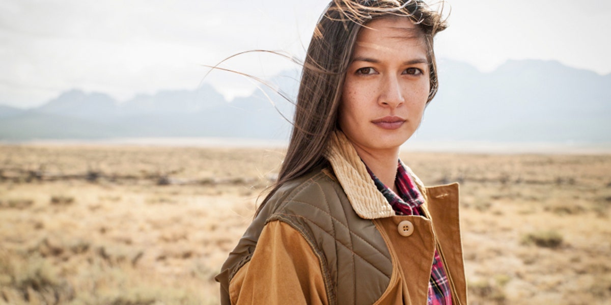 woman standing in desert in brown coat