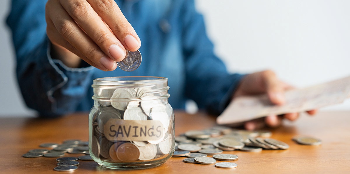 man putting coins in jar