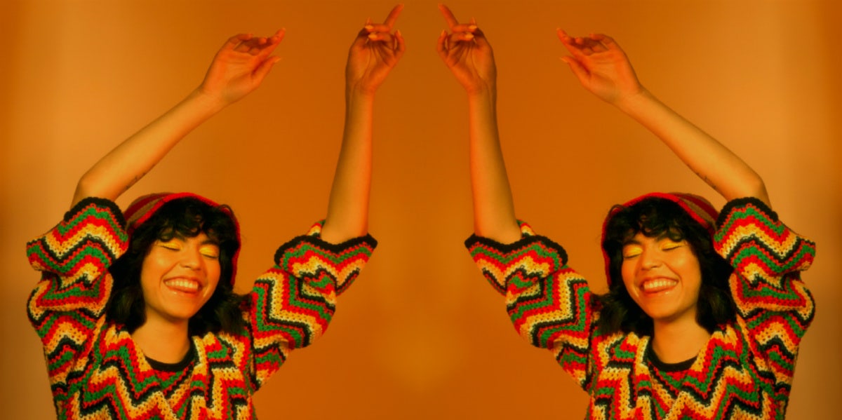 woman with her arms up in the air on orange background