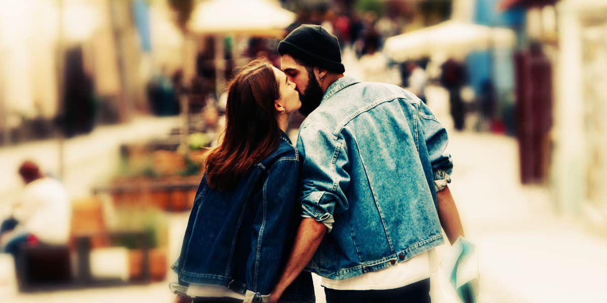 couple walking down the road sharing a kiss