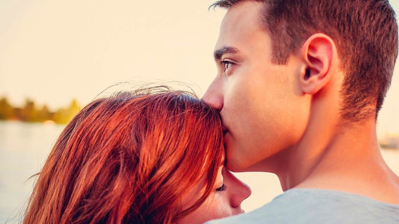 Handsome young man kissing his girlfriend near the river