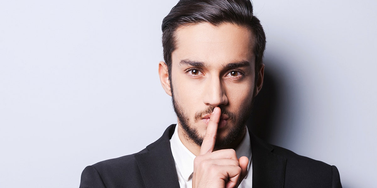 8 Small Secrets Men Hide From Wives man putting up a whisper sign in front of face